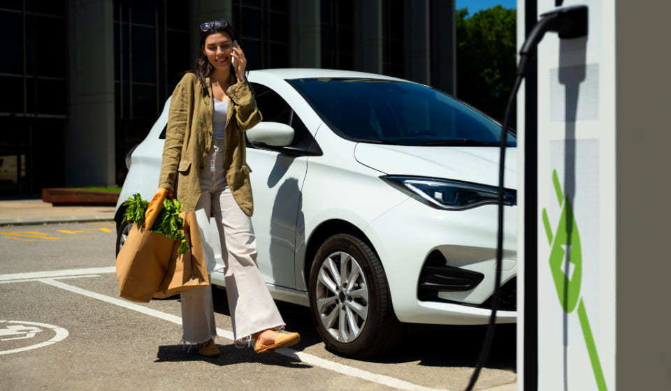 ¿Cuánto cuesta cargar un coche eléctrico en una gasolinera? Mujer cargado coche eléctrico en una gasolinera